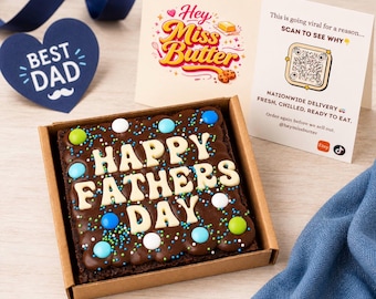 May include: A chocolate brownie in a cardboard box, decorated with white frosting that spells out "HAPPY FATHERS DAY". The brownie is adorned with colorful sprinkles and candies. A card with the text "Hey Miss Butter" and a "Best Dad" heart-shaped decoration are also present.