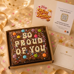 May include: A square chocolate brownie in a cardboard box, topped with white chocolate lettering that reads SO PROUD OF YOU, colorful candy-coated chocolates, and sprinkles. Includes a card with a QR code and the text Hey Miss Butter.
