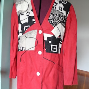 Peut inclure: Un blazer rouge avec un col en V et trois boutons blancs. Le blazer présente un motif patchwork sur le haut de la poitrine avec des motifs abstraits noirs et blancs. Il a deux poches avant et des manches longues.