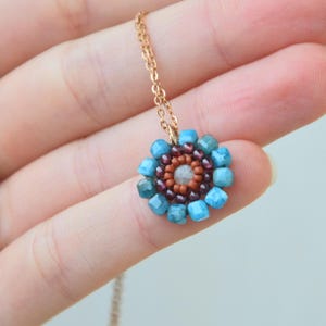 The gemstones used are natural. The blue ones are Apatite, with the shades of a calm sea; the purple ones are Mozambique Garnet, the colour of red wine; and the lightest bead is Aquamarine. The brick/orange beads are made of glass.