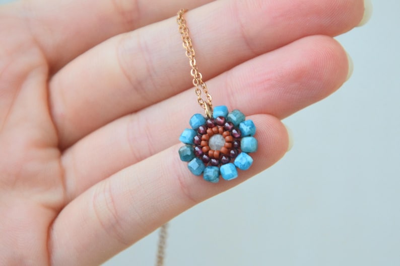 The gemstones used are natural. The blue ones are Apatite, with the shades of a calm sea; the purple ones are Mozambique Garnet, the colour of red wine; and the lightest bead is Aquamarine. The brick/orange beads are made of glass.