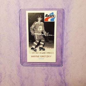 May include: A black and white hockey card featuring Wayne Gretzky, a professional ice hockey player, wearing a white jersey with the word "Racers" on it. The card has a red, white and blue logo with the word "Racers" on it. The card also has the text "Wayne Gretzky" and "Centre" on it.
