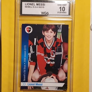 Pode incluir: Um cartão colecionável de Lionel Messi do Newell's Old Boys, temporada de 2000 (U12), classificado como Gem Mint 10. O cartão apresenta uma foto de Messi jovem com uma camisa vermelha e preta. O cartão está em um suporte protetor.