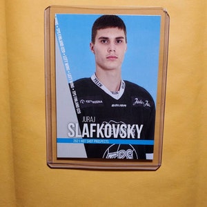 Könnte beinhalten: Eine Hockey-Sammelkarte mit Juraj Slafkovsky, einem jungen Hockeyspieler, der ein schwarz-weißes Trikot mit dem Text "Jalo Jar" auf der Vorderseite trägt. Die Karte stammt aus der Serie 2021 Hot Shot Prospects.