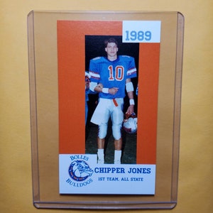 May include: A vintage football trading card featuring a player in a blue jersey with the number 10. The card is orange and white with the text "1989" in the top right corner. The player's name is "CHIPPER JONES" and the text "BOLLES BULLDOGS 1ST TEAM, ALL STATE" is below the player's image.