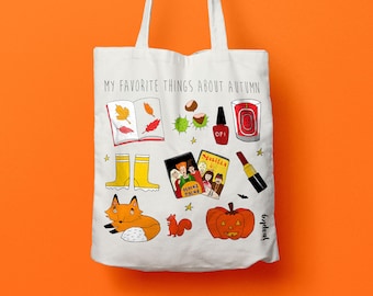 May include: White tote bag with the text "My Favorite Things About Autumn" and illustrations of fall-themed items, including a book, leaves, a pumpkin, a fox, a squirrel, rain boots, nail polish, a candle, and a lipstick.