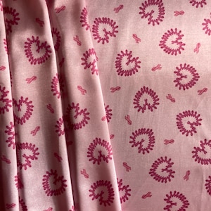 Puede incluir: Tela rosa claro con un patrón repetido de formas de corazón y lazos rosas. Los corazones son de un rosa más oscuro, con un diseño texturizado. La tela está doblada, mostrando la repetición del patrón.