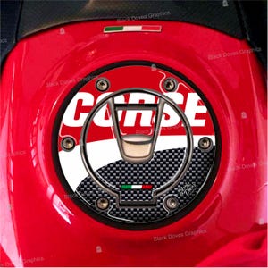 Op de afbeelding: Een rode, witte en zwarte motorfiets tankdop cover met het woord "CORSE" in witte letters. De cover heeft een carbon fiber patroon en een kleine Italiaanse vlag.