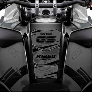 Może przedstawiać: Czarny zbiornik paliwa motocyklowego z czarną i szarą naklejką graficzną. Naklejka zawiera tekst "Triple Black", "GS", "R1250 ADVENTURE" i wzór kompasu.