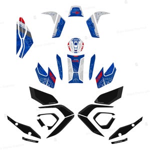 May include: Motorcycle graphic decals in blue, white, red, and black. The decals feature compass and map designs, with the word "ADVENTURE". The decals are arranged on a white background.