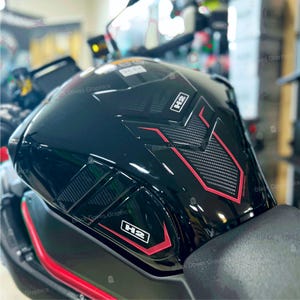 Può includere: Serbatoio nero lucido per moto con dettagli rossi e in fibra di carbonio. Il serbatoio presenta la scritta "H2" in un rettangolo bianco e le parole "Black Doves Graphics" sono visibili. Il design include forme e linee geometriche.