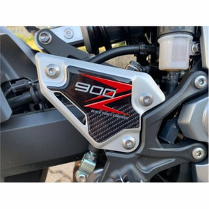 May include: Close-up of a motorcycle with a silver and black carbon fibre sticker that says "900" in red and "Black Doves Graphics" in black.