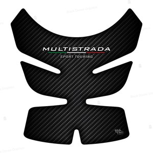 Peut inclure: Protecteur de r&eacute;servoir de moto en fibre de carbone noire avec le mot "MULTISTRADA" en blanc et "SPORT TOURING" en dessous. Le design a un motif textur&eacute; et une forme unique, avec un petit logo "Black Doves Graphics".