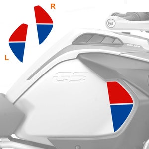 Op de afbeelding: Een witte motorfiets benzinetank met een rode en blauwe sticker aan de rechterkant. De sticker heeft de tekst "GS" erop. De tank heeft een zwart "Rallye" logo bovenop.