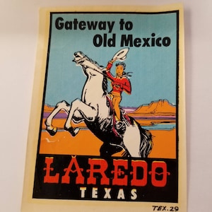 May include: Vintage travel sticker featuring a cowboy riding a white horse with a blue, orange, and purple landscape in the background. The text reads "Gateway to Old Mexico Laredo Texas TEX. 29".