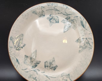 May include: A white ceramic plate with a blue and white ivy design. The plate has a slightly raised rim and a smooth, glossy finish.