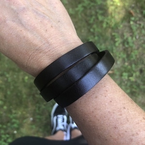May include: A black leather bracelet wrapped around a wrist three times.