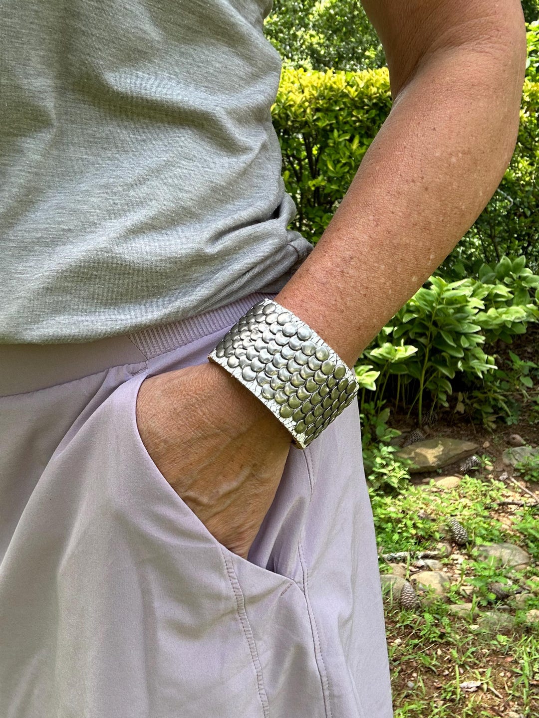 Bracciale largo in pelle con borchie metalliche piatte sovrapposte