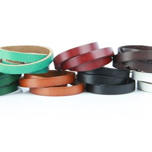 May include: A selection of leather belts in various colours, including green, brown, black, white, and burgundy. The belts are thin and appear to be for women's wear, with a silver buckle on the white belt.
