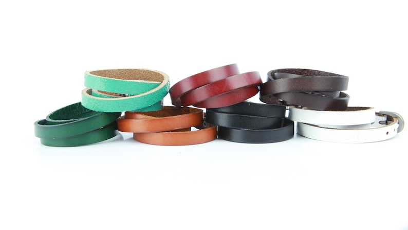 May include: A selection of leather belts in various colours, including green, brown, black, white, and burgundy. The belts are thin and appear to be for women's wear, with a silver buckle on the white belt.