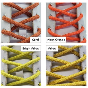 Op de afbeelding: Close-up van vier paar veters in verschillende kleuren: koraal, neonoranje, felgeel en geel. De veters zijn in een kruispatroon op een witte schoen geknoopt.