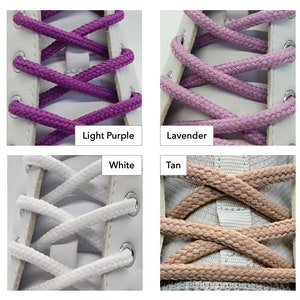 Op de afbeelding: Vier paar veters in verschillende kleuren: lichtpaars, lavendel, wit en bruin. De veters zijn in een kruispatroon geknoopt op een witte canvas schoen.