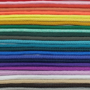 May include: A collection of 20 different colored cords, arranged in rows, against a white background. The cords are all the same thickness and texture, and they are all made of a woven material.