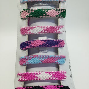 May include: A white shoe with colorful patterned shoelaces. The shoelaces are pink, blue, green, purple, white, and black.