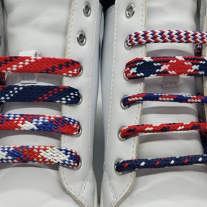 May include: A pair of white sneakers with red, white, and blue shoelaces. The shoelaces are woven in a plaid pattern.