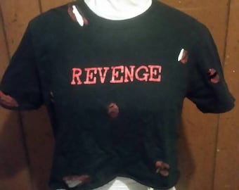 May include: Black crop top with the word "REVENGE" in red lettering. The shirt has distressed details with red accents. The shirt is displayed on a mannequin.