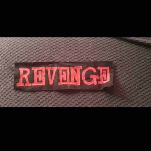 May include: A black fabric patch with the word "REVENGE" embroidered in red.
