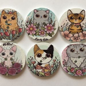 May include: Six round wooden buttons featuring colourful cat illustrations and floral designs. Each button has two holes for sewing. The cats are depicted in various poses and colours, including orange, grey, and calico.