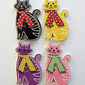 May include: Four wooden cat-shaped buttons in black, yellow, purple, and pink. Each cat wears a scarf with white polka dots. The black and yellow cats have red scarves, while the purple and pink cats have yellow and green scarves.