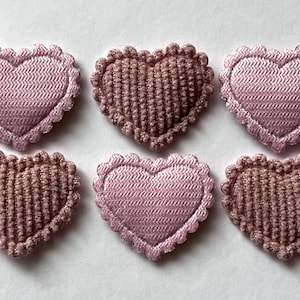 Peut inclure: Six cœurs en tissu rose avec des bords festonnés. Trois cœurs sont d'une nuance de rose plus foncée et trois sont d'une nuance de rose plus claire.