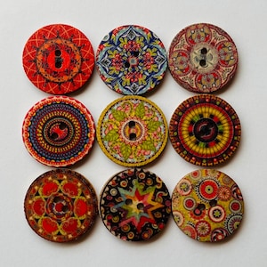 May include: A set of nine circular wooden buttons arranged in a three-by-three grid. Each button features a unique, intricate, and colorful printed pattern, including geometric shapes, floral motifs, and star designs, all with two central holes.
