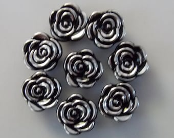 Può includere: Otto bottoni a forma di rosa di colore argento con centri neri.