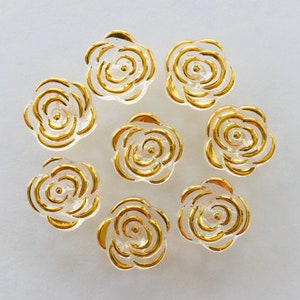 May include: Eight clear glass rose-shaped buttons with gold trim. The buttons are arranged in a circle on a white background.