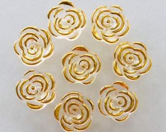 May include: Eight clear glass rose-shaped buttons with gold trim. The buttons are arranged in a circle on a white background.