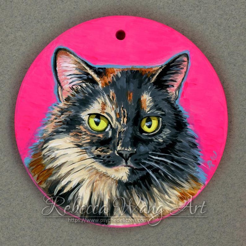 May include: A close-up portrait of a calico cat with green eyes painted on a round, hot pink background. The cat is looking directly at the viewer. The painting is signed "Rebecca Wang Art" and includes the website "https://www.psychedeliczen.com".