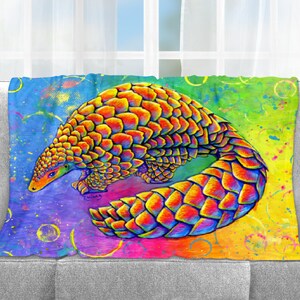 May include: A colorful painting of a pangolin on a rainbow background with yellow, orange, red, blue, green, and purple paint splatters. The pangolin is curled up with its tail wrapped around its body. The painting has a whimsical and abstract style.