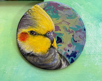 Cacatúa redonda de 7'' x 1/4'', gris con cabeza amarilla, acrílico sobre tabla de madera marmolada.