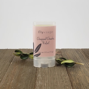 May include: A pink and white tube of Chapped Cheeks Relief balm by lily & sage. The tube is labeled with the product name and net weight of 0.5 oz (13 g).