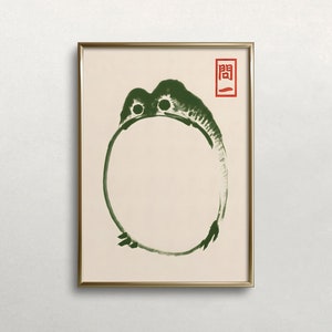 May include: A framed art print featuring a green abstract frog-like creature encircling a blank space. The artwork has a minimalist style with a red Japanese character in the upper right corner. The frame is gold.