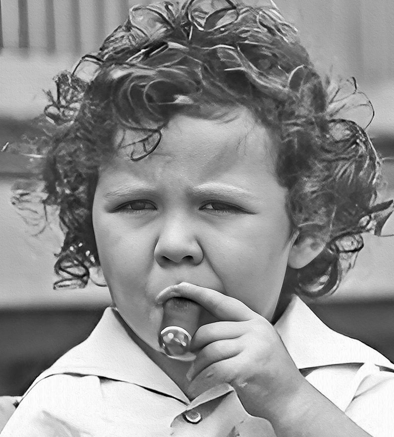 Peut inclure: Un jeune enfant aux cheveux boucl&eacute;s tient un cigare dans sa main et regarde la cam&eacute;ra.