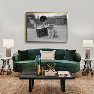 May include: Black and white framed photograph of a dog wearing headphones, sitting next to a vintage radio with a large horn speaker. The image is displayed above a green velvet sofa, with side tables and lamps on either side.