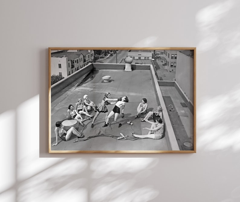 Puede incluir: Fotograf&iacute;a en blanco y negro de un grupo de personas en una azotea. Dos personas est&aacute;n boxeando, mientras que otras est&aacute;n sentadas. La imagen est&aacute; enmarcada en un borde de madera, capturando una escena vintage.