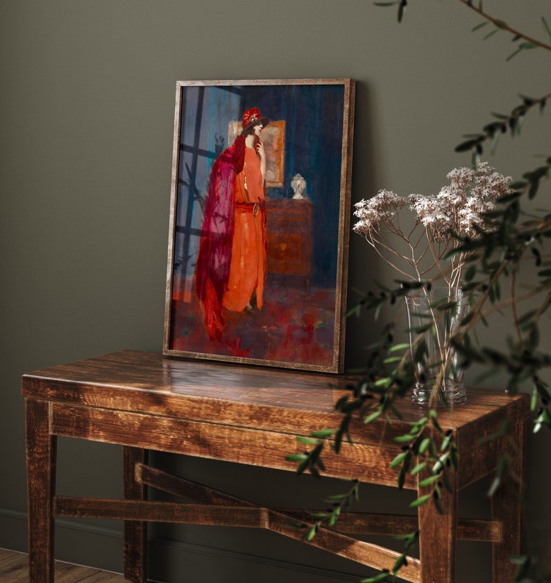 May include: A framed painting of a woman in a red and orange dress standing in a room with a blue wall. The woman is wearing a red hat and is looking at a mirror.