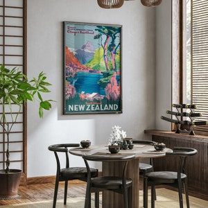 May include: A vintage travel poster for New Zealand featuring a scenic landscape with mountains, a lake, and trees. The poster is framed and hanging on a wall in a dining room with a wooden table and black chairs.