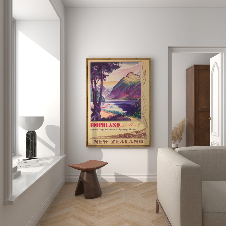 Puede incluir: Un p&oacute;ster de viaje vintage enmarcado para Fiordland, Southland, Nueva Zelanda. El p&oacute;ster presenta un paisaje esc&eacute;nico con monta&ntilde;as, un lago y un &aacute;rbol. El texto dice "Fiordland, Southland" y "Scenic Trip by Train & Railway Motor."