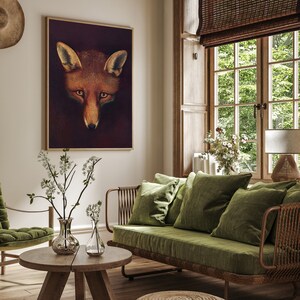 May include: A living room interior with a green velvet sofa, a wooden coffee table, and a framed print of a fox's face. The room has a rustic feel with wooden floors and a window with a bamboo blind.
